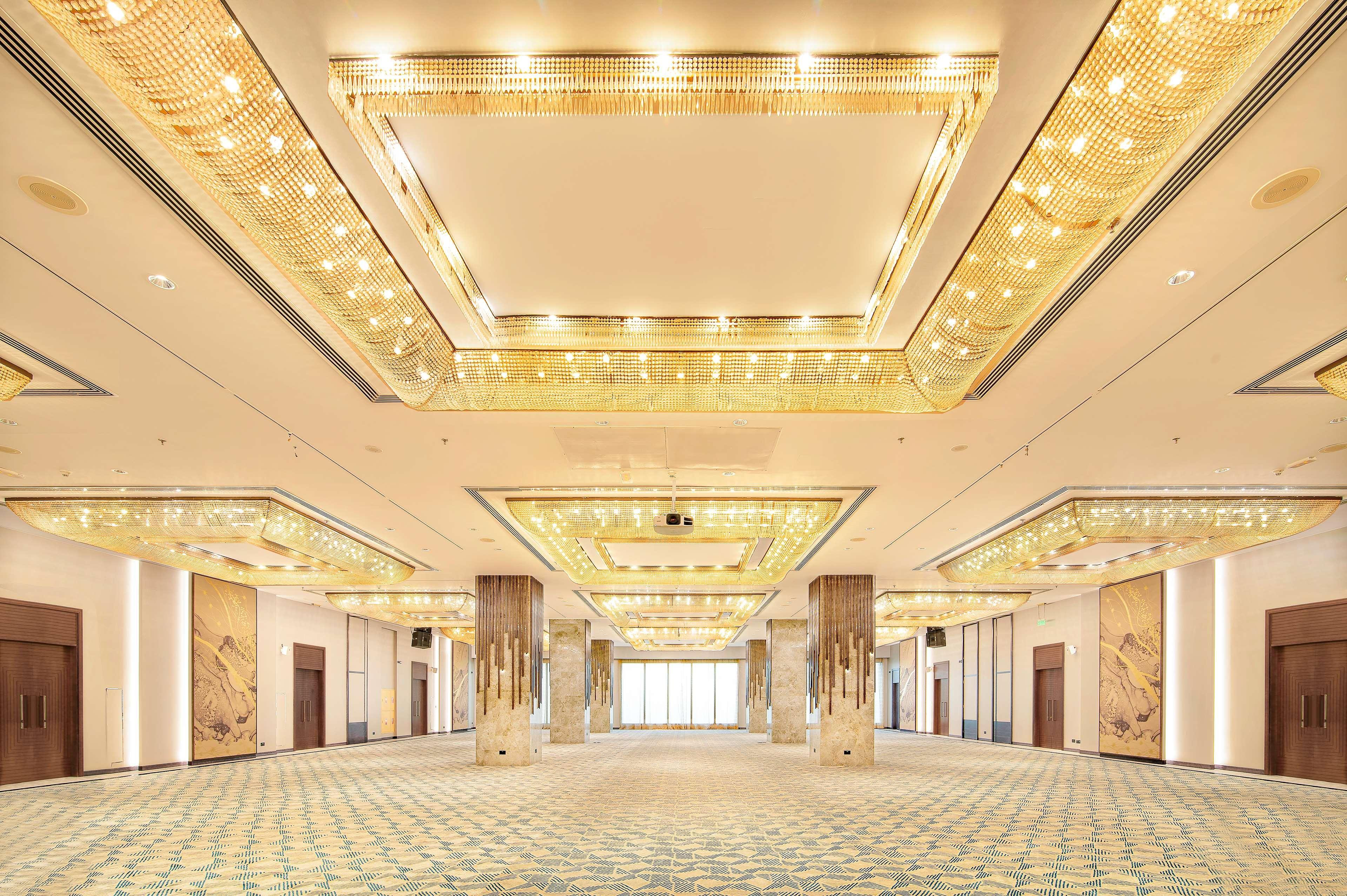 Radisson Blu Hotel & Resort, Abu Dhabi Corniche Екстериор снимка The photo shows a spacious, elegantly designed interior, likely a banquet or conference hall. The ceiling features a luxurious design with intricate lighting elements that give off a warm glow. The floor is covered with a patterned carpet in soft col
