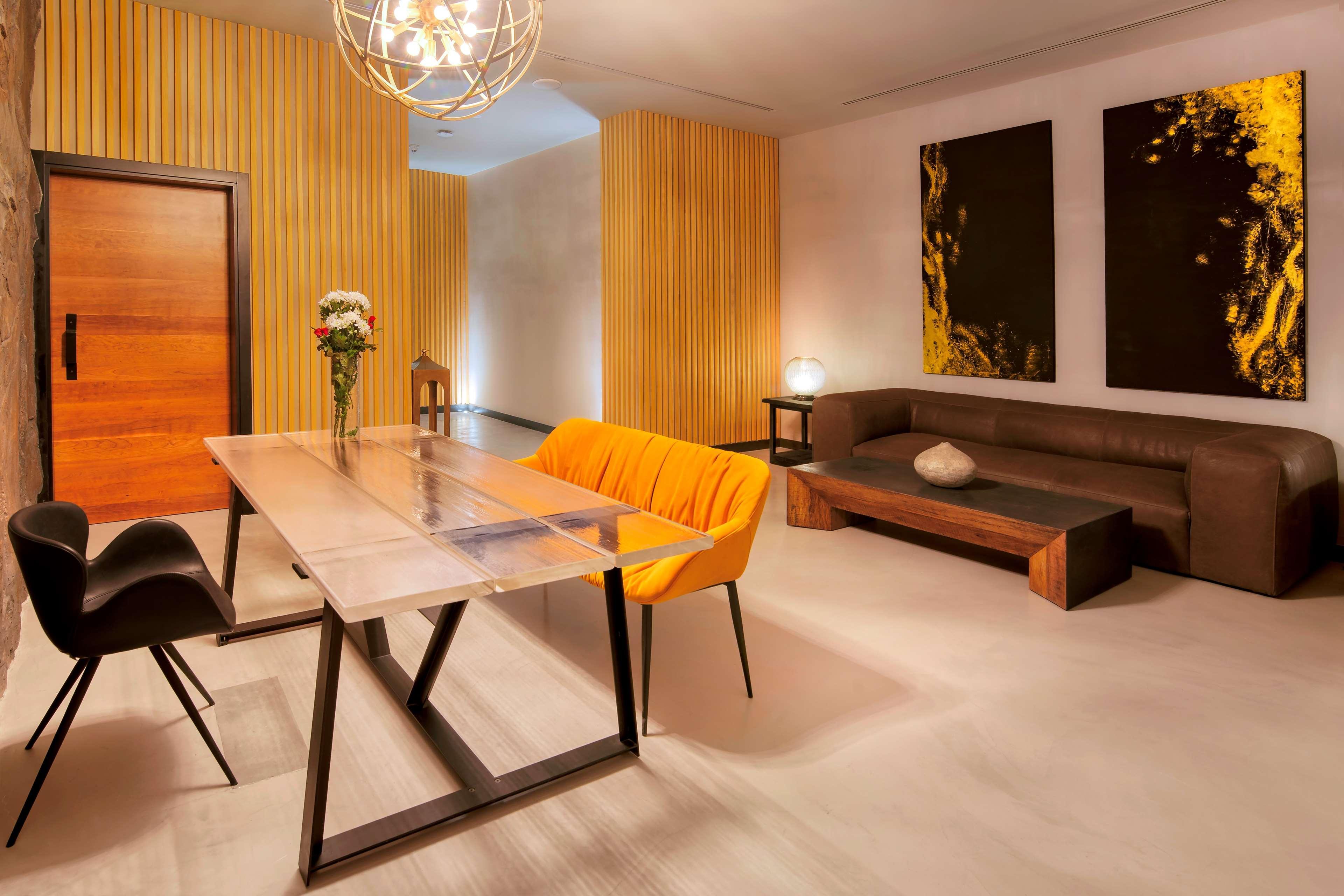 Radisson Blu Hotel & Resort, Abu Dhabi Corniche Екстериор снимка The photo shows a modern and stylish interior space. There is a minimalist dining or meeting table made of glass and metal, surrounded by black chairs. One of the chairs is bright orange, adding a pop of color to the room. In the background, there is