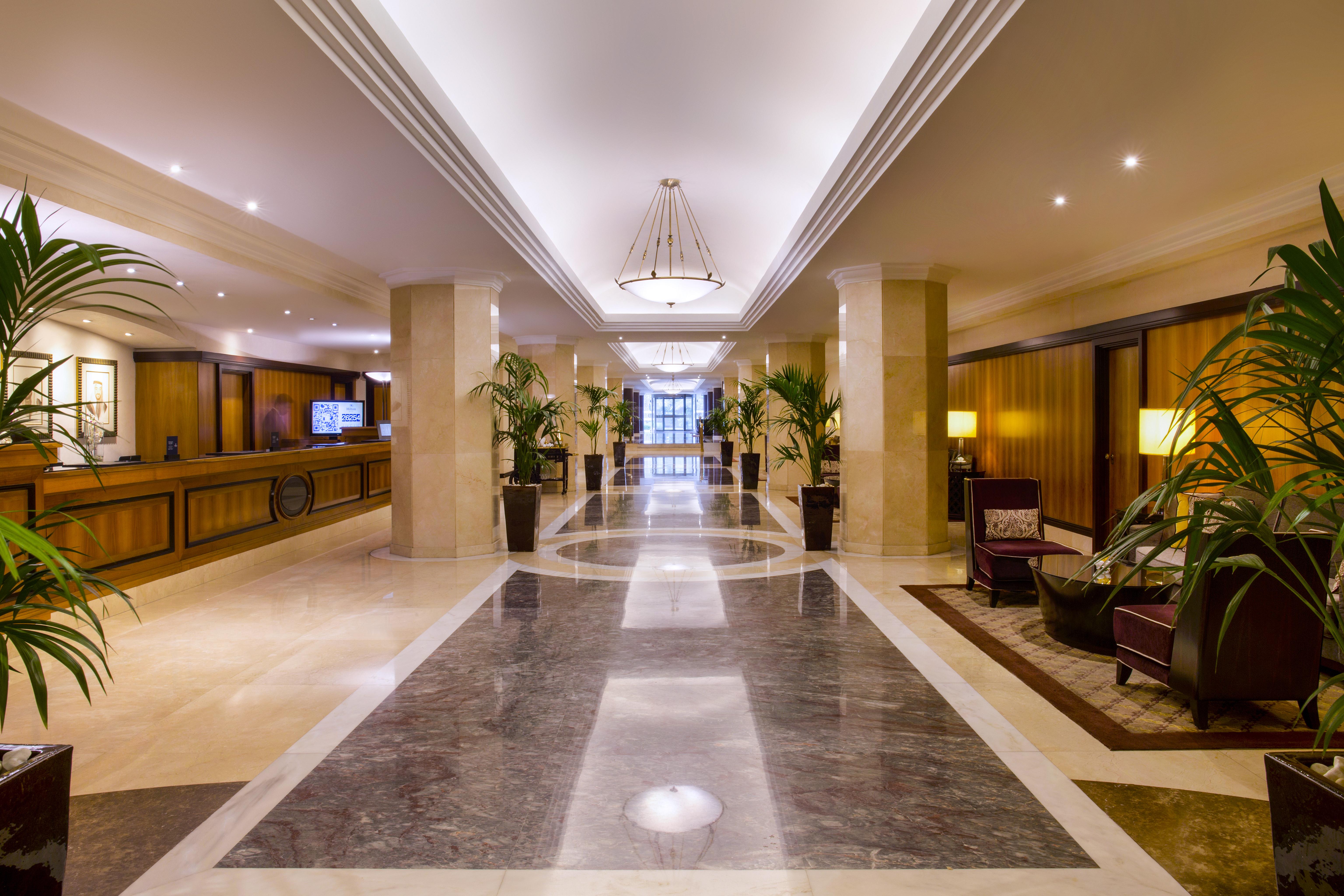 Radisson Blu Hotel & Resort, Abu Dhabi Corniche Екстериор снимка The photo displays an elegant hotel lobby. It features a spacious hallway with polished marble flooring and decorative lighting. On either side of the corridor are tall potted plants, adding a touch of greenery to the space. The reception desk is vis