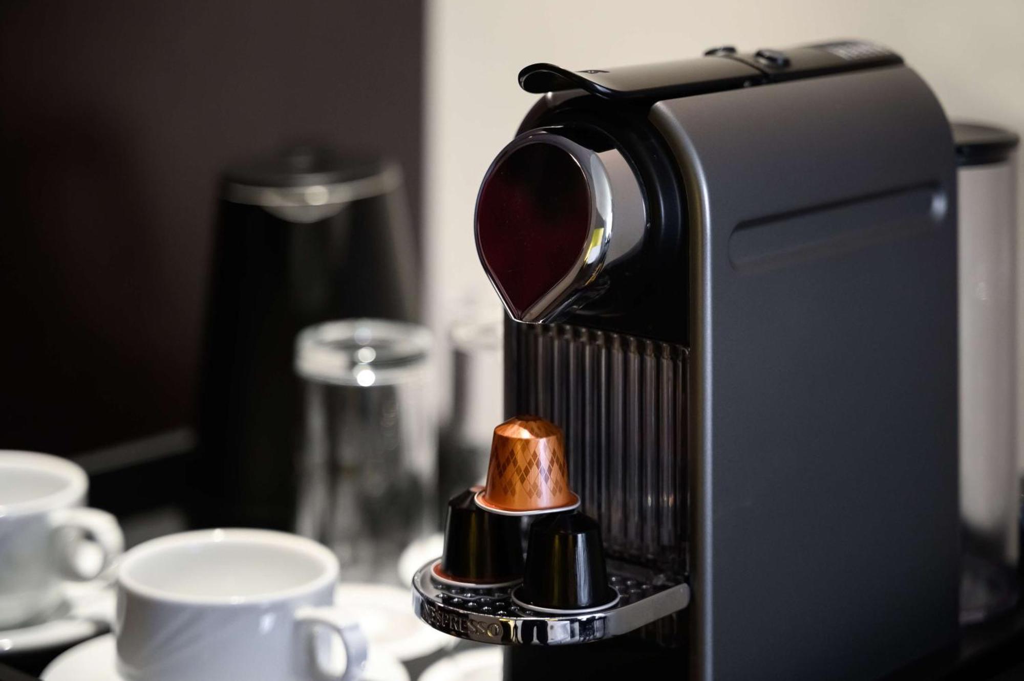 Radisson Blu Hotel & Resort, Abu Dhabi Corniche Екстериор снимка The photo shows a sleek, modern coffee machine, likely a Nespresso model, in the process of brewing coffee. The machine is primarily black with a shiny finish. There is a cup placed underneath the spout, which is dispensing a stream of dark coffee. N